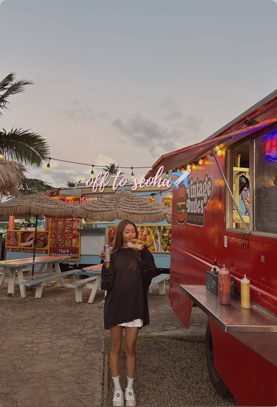Female traveler holding a juicy double smash burger from Vintage Dudes food truck in Hawaii