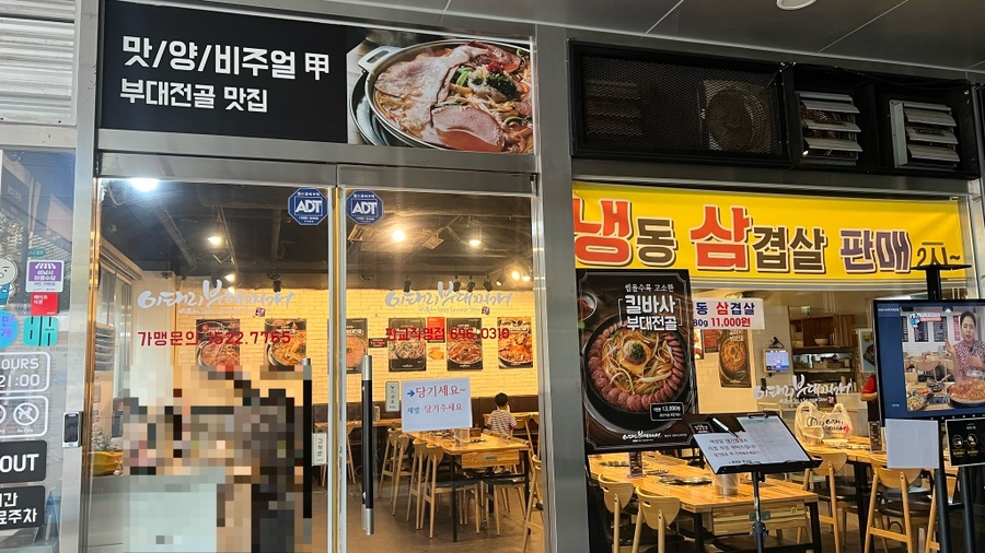 간판과 통유리 출입문, 냉동 삼겹살 현수막이 걸린 식당 정면 전경